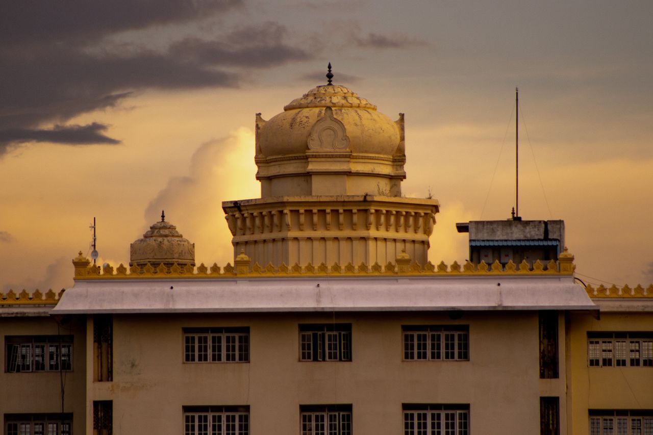 creative-03 A stunning view of colonial architecture in Bengaluru against a dramatic sunset sky.