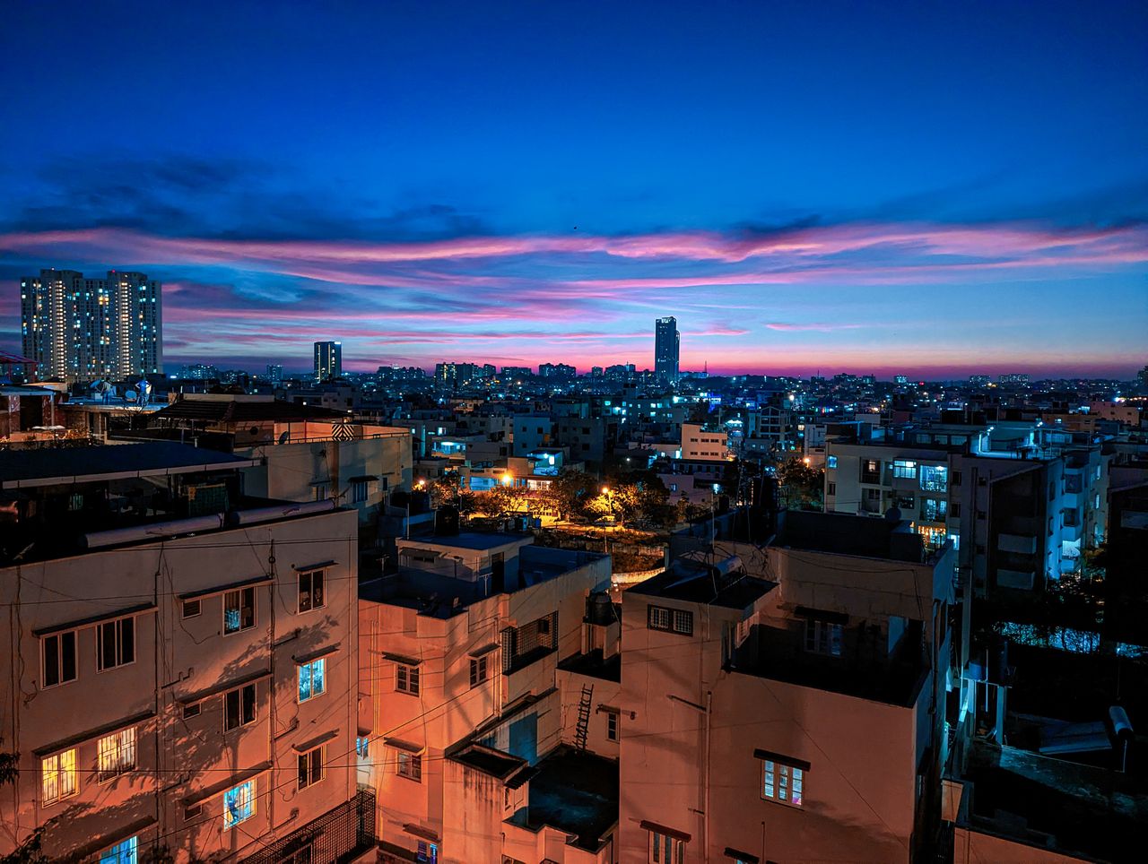 brand-01 Stunning view of Bengaluru cityscape illuminated at dusk, showcasing modern architecture under a vivid sunset sky.