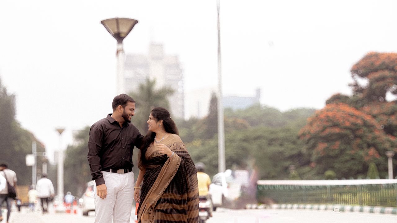 creative-03 A smiling couple walks arm in arm in an urban park during the day.